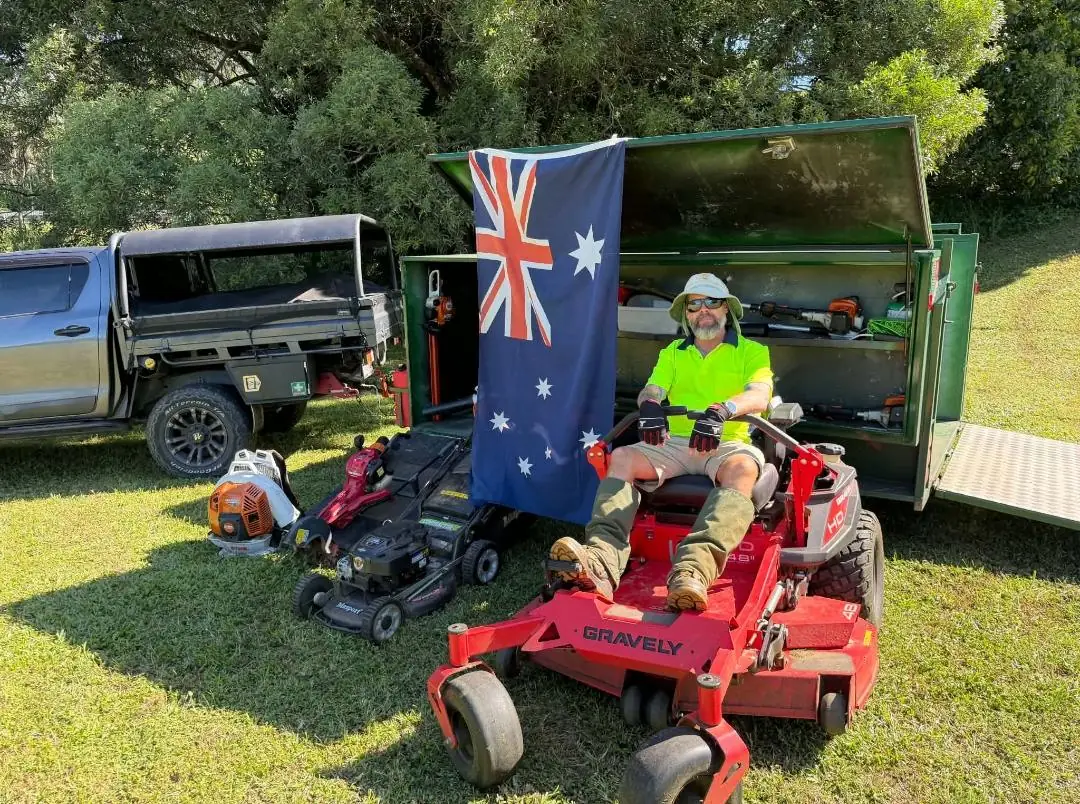 Cale seated on his Gravely zero-turn mower in front of his equipment trailer