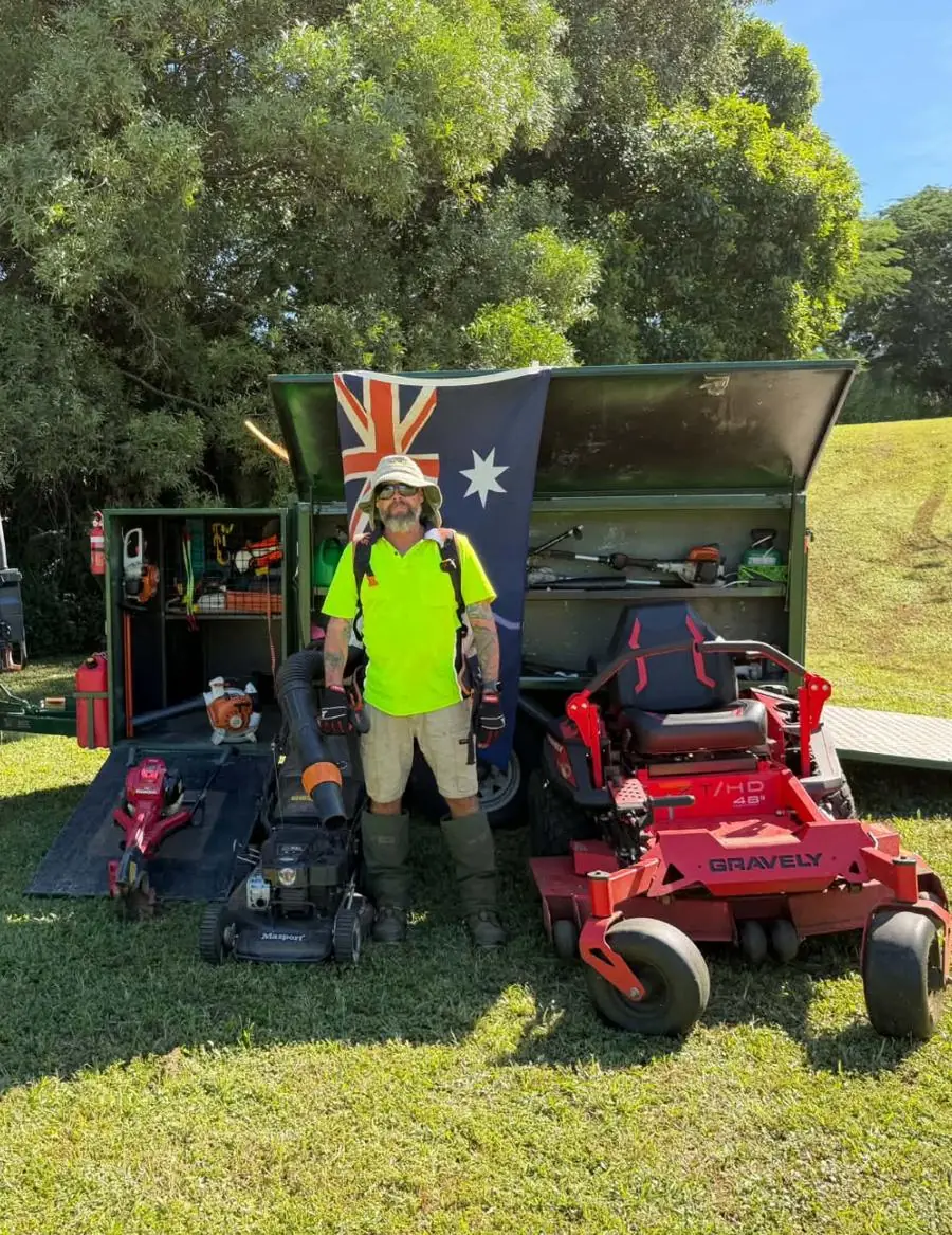 Cale standing with his ride-on mower, push mower and tool trailer